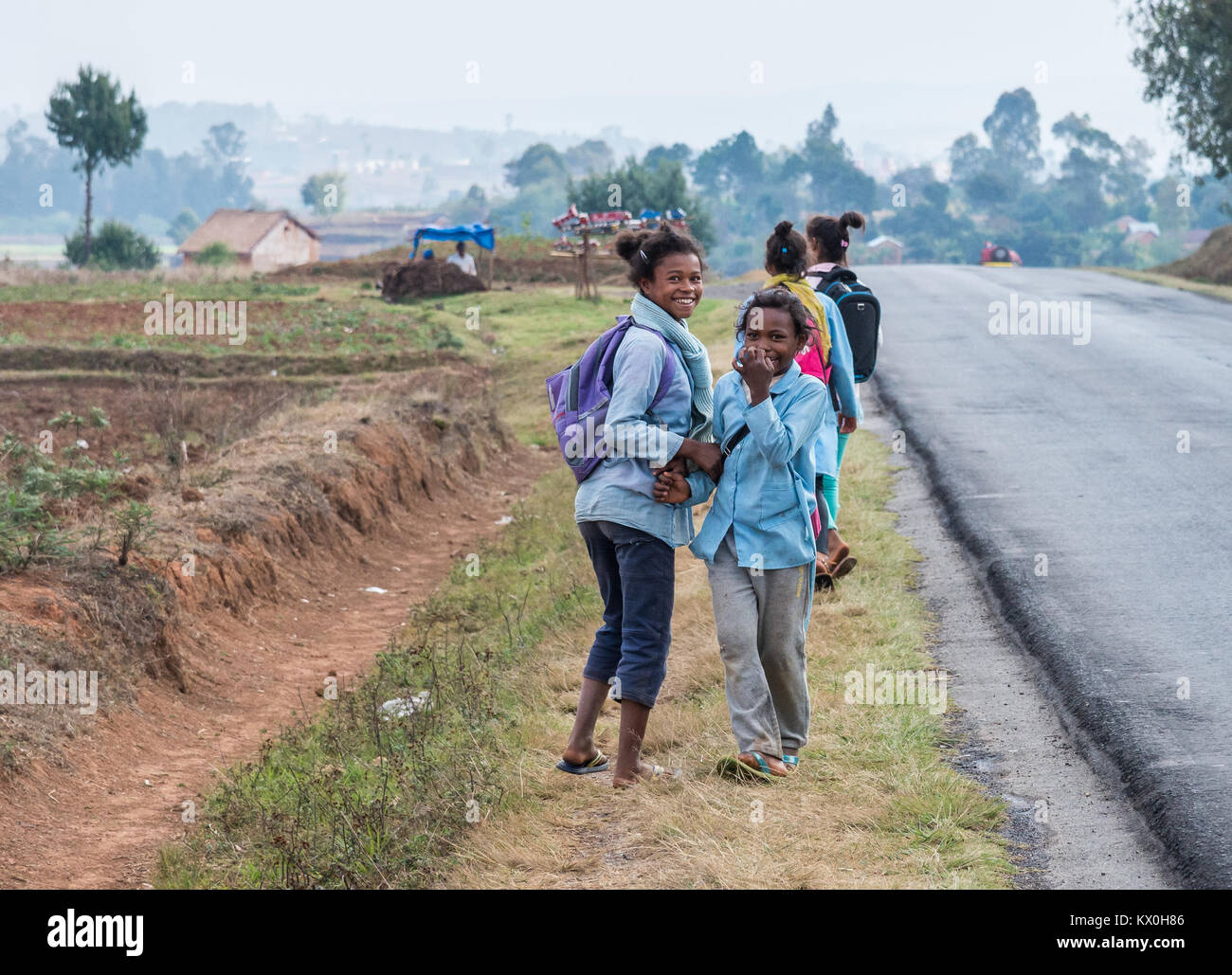 School girls in uniform walk on the side of road. Madagascar, Africa. Stock Photo