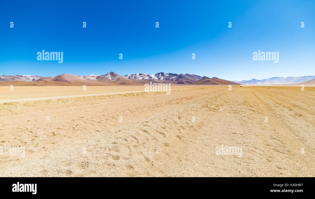 Dirt road at high altitude with sandy desert and barren volcano range on the Andean highlands. Road trip to the famous Uyuni Salt Flat, travel destina Stock Photo