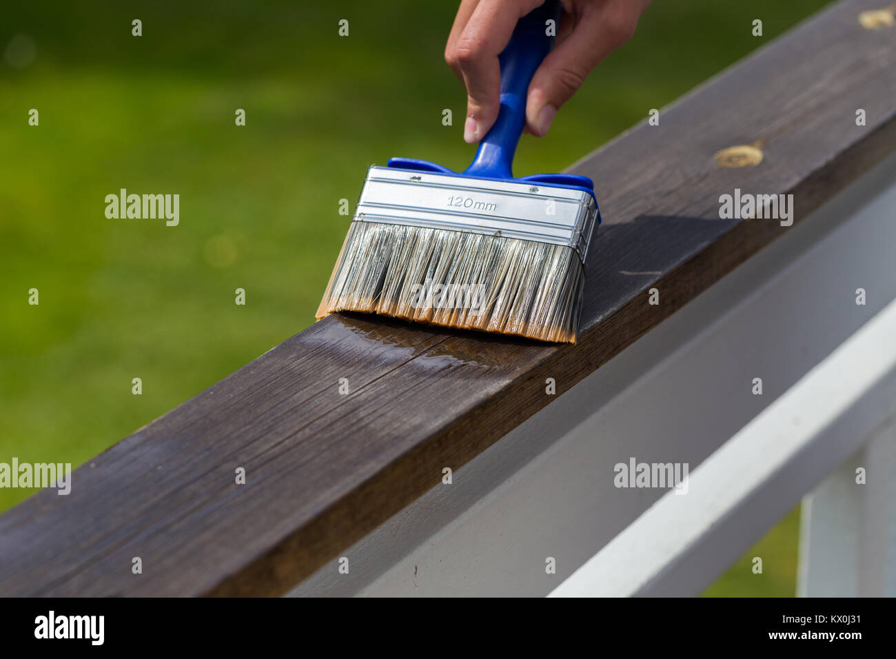 Oiling Terrace Rail with Wide Brush painting wooden patio deck with