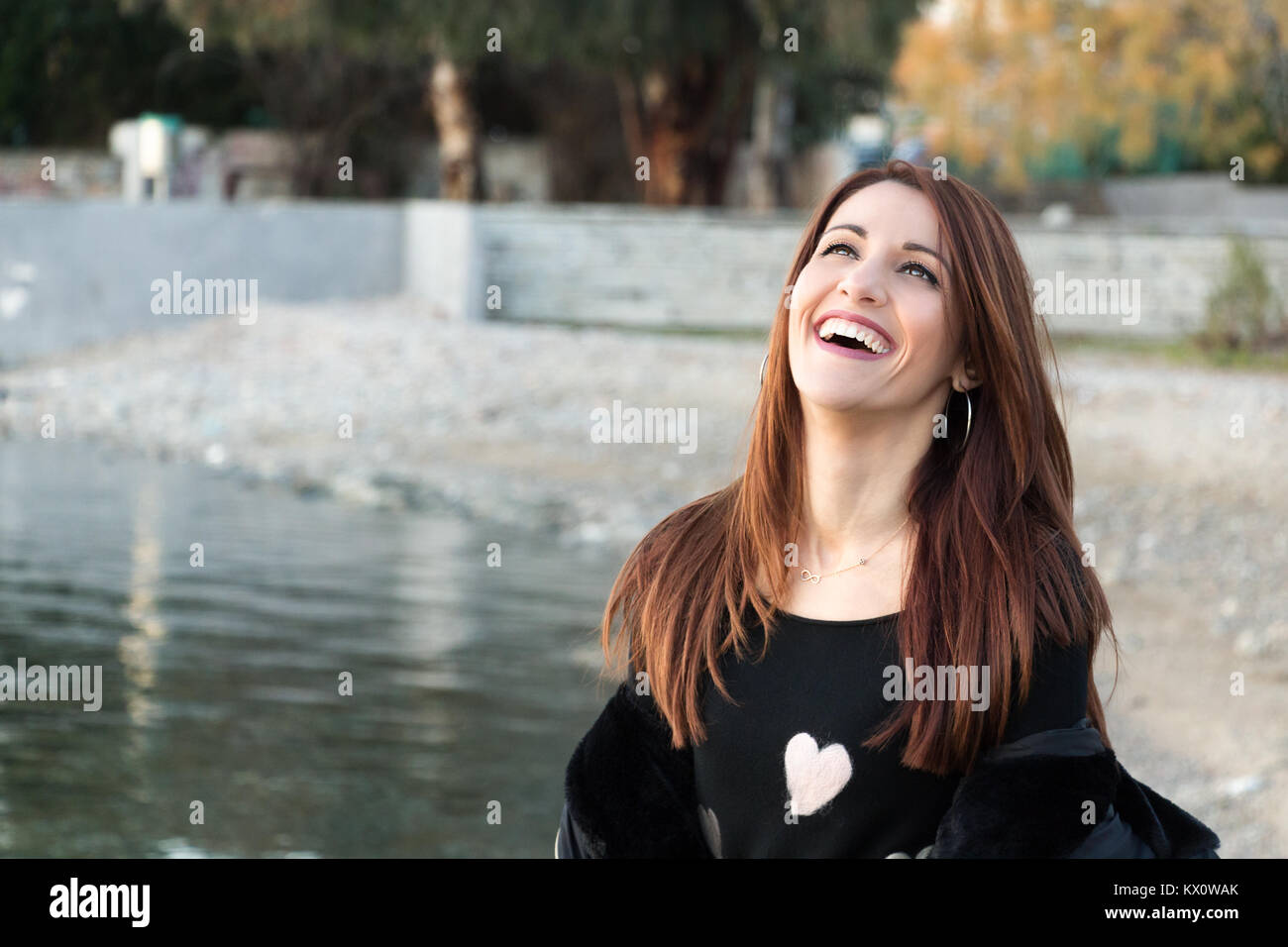 Portrait of a woman laughing spontaneously, cheerful, outdoors, looking up. Stock Photo