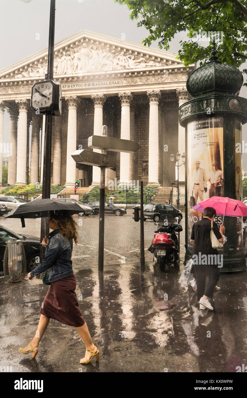 France, Paris, Church of the Madeleine, Woman walking in the rain with umbrella. Stock Photo