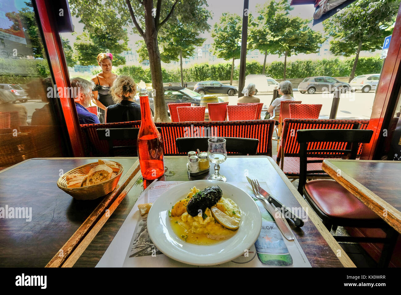 France, Paris, Lunchtime in a bistro with a view through an open window on trees and the terras of the restaurant Stock Photo
