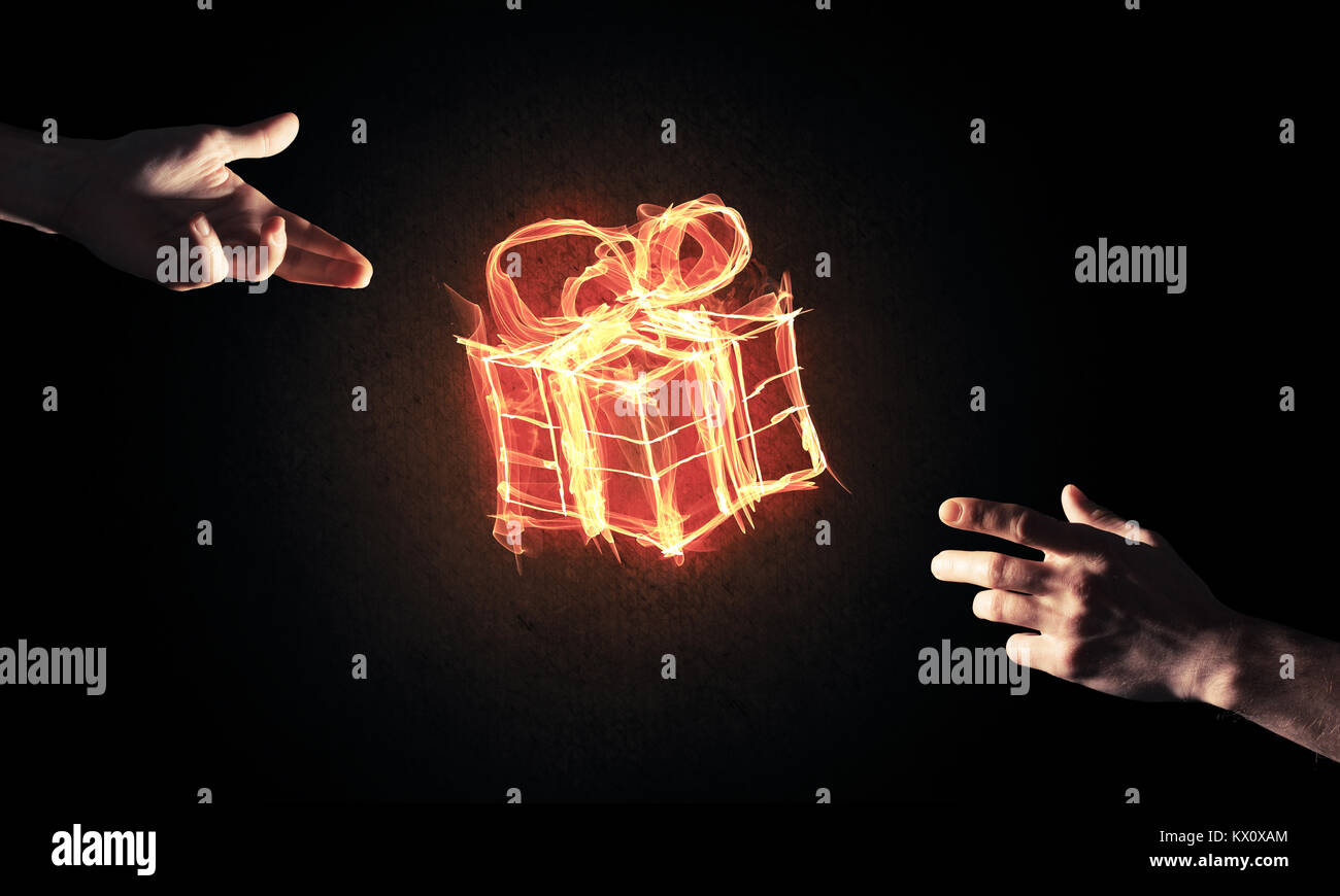 Glowing fire gift box icon in palm on dark background Stock Photo - Alamy