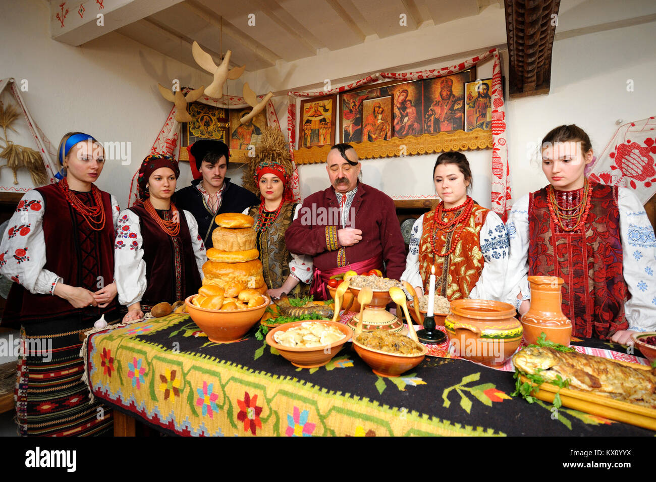 People in Ukrainian native dresses standing behind table to celebrate Christmas Eve. Reconstruction of folk traditions. January 4, 2018. Kiev, Ukraine Stock Photo