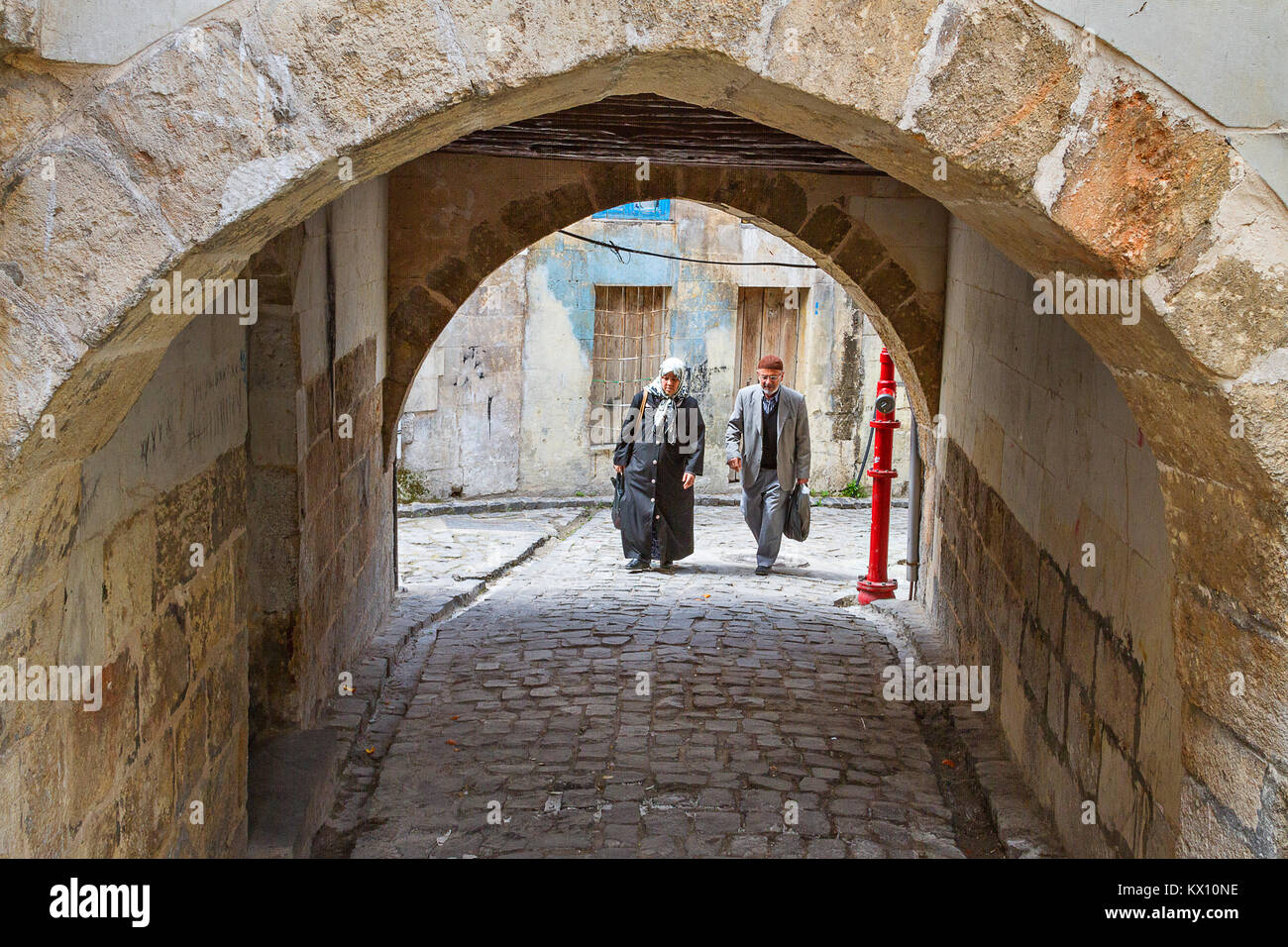 Elderly couple walking in the old narrow street with an archway, in Gaziantep, Turkey. Stock Photo