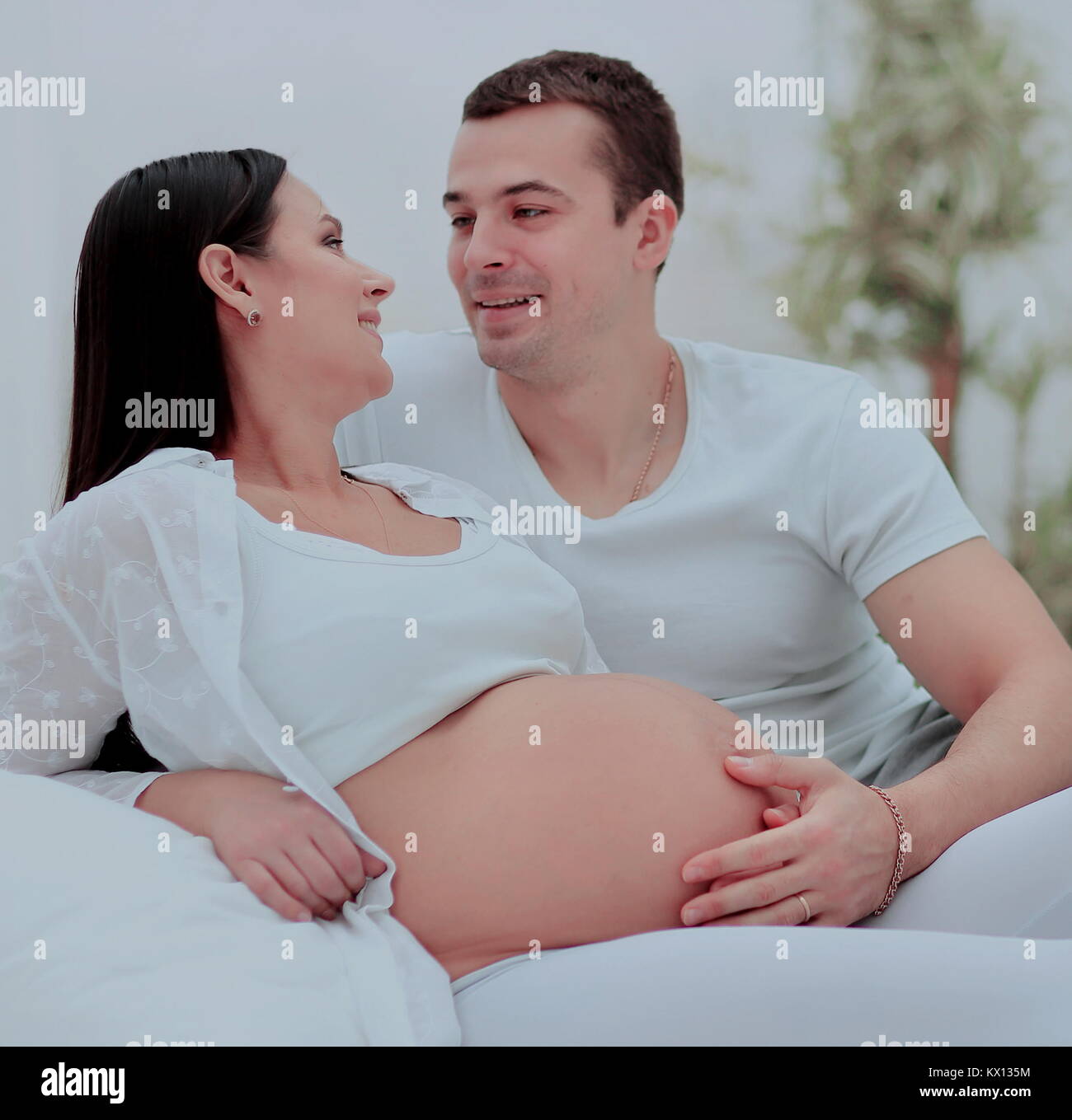 Pregnant wife relaxing on husband lap at home Stock Photo Alamy