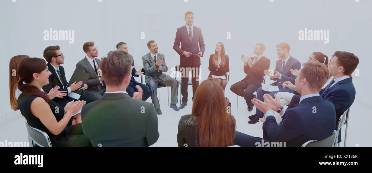 business team sitting on the chairs standing in a circle, clapping to ...