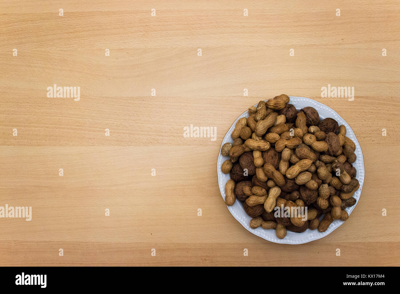 plate of nuts on wooden table with negative space Stock Photo