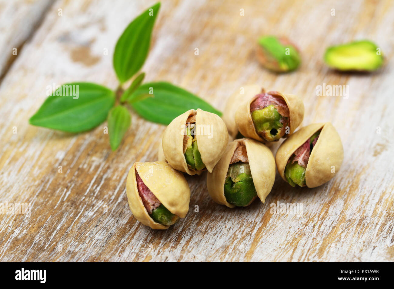 Few open pistachio nuts in nutshell on rustic wooden surface Stock Photo