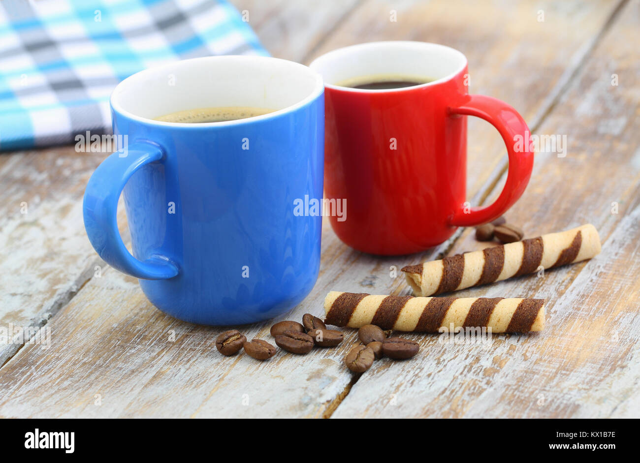 Two colorful coffee mugs and crunchy wafers on rustic wooden surface Stock Photo