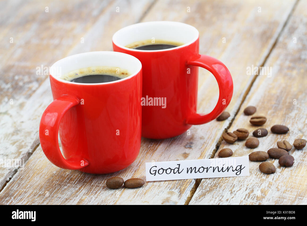 Good morning card with two red mugs of coffee and coffee beans on rustic surface Stock Photo
