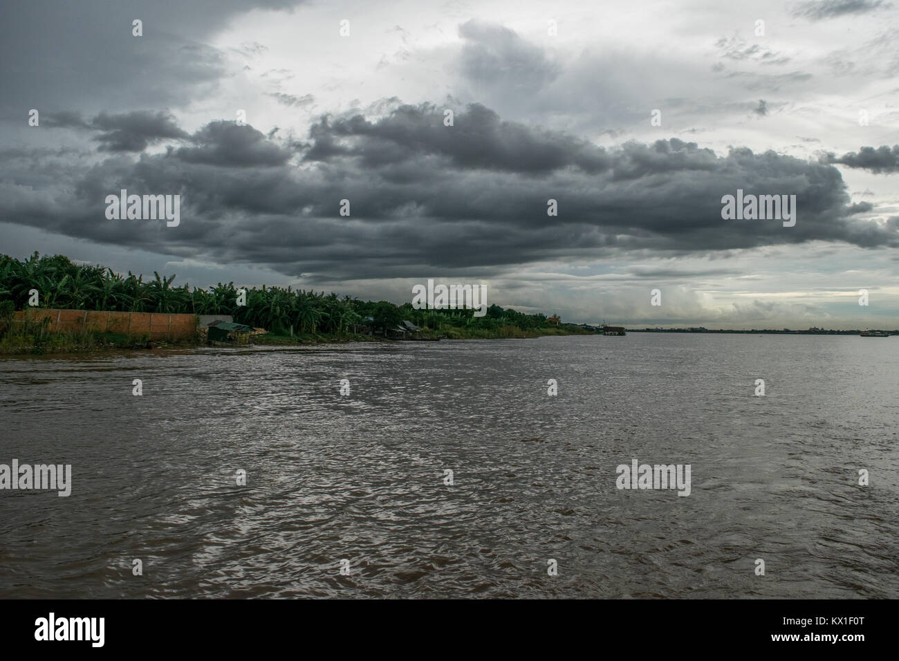 A patch of low dark thick clouds floating over the Mekong river, river bank. Rainy clouds during Monsoon season in Phnom Penh, Cambodia, SE Asia Stock Photo