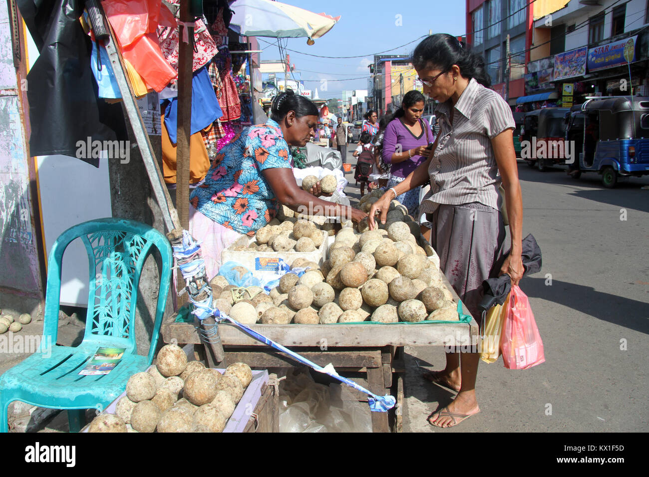 PANADURA, SRI LANKA - CIRCA DECEMBER 2013 woman sell stone apple on the street. Stoneapple is a native fruit of Sri Lanka Stock Photo