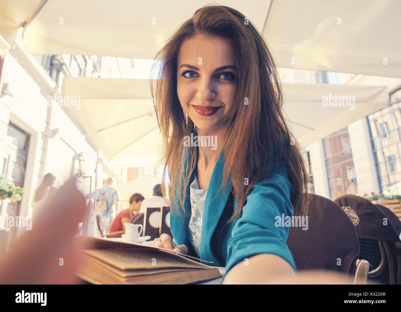 Close up portrait of a young attractive woman holding a smartphone digital camera with her hands and taking a selfie self portrait of herself while networking. Stock Photo