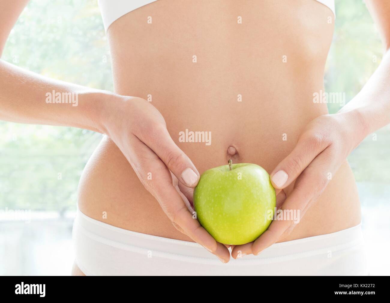 MODEL RELEASED. Young woman holding green apple, close up. Stock Photo