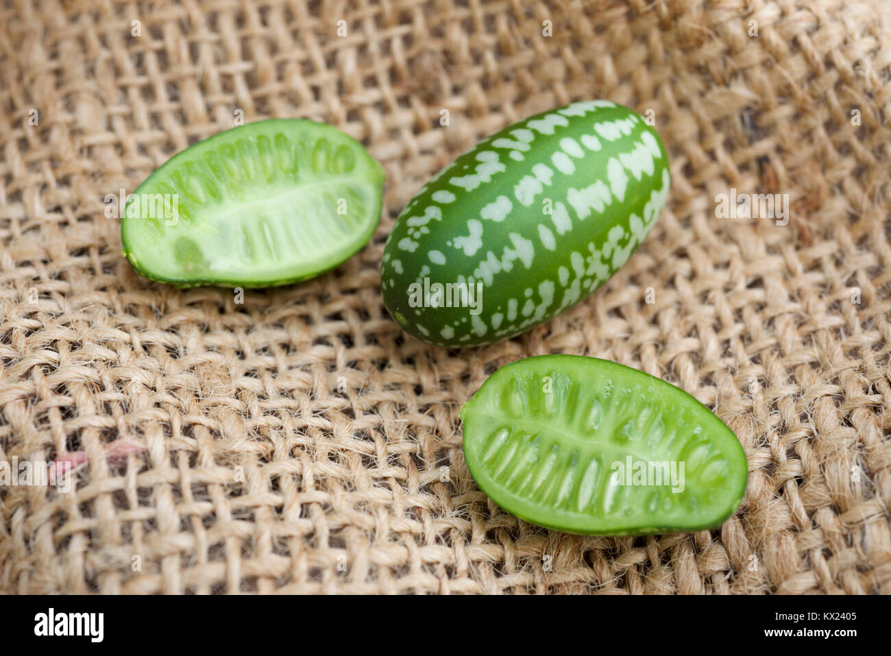 Cucamelon fruit, also known as Mexican gherkins, Mexican sour cucumbers, or Melothria Scabra on a hessian, burlap sack background, whole and cut fruit. Stock Photo