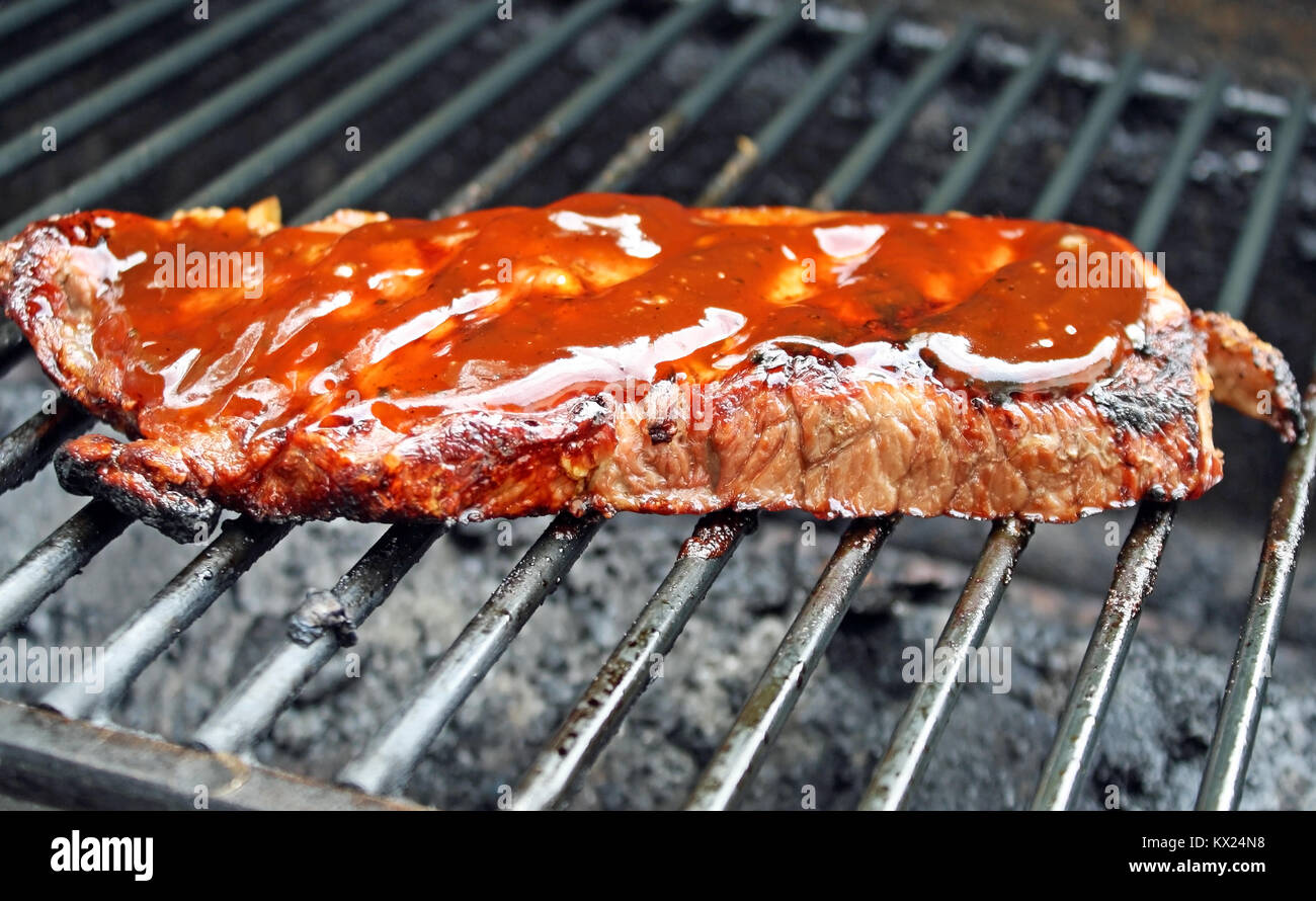 Juicy Sirloin Steak with Barbecue Sauce Cooking on The Grill Stock Photo