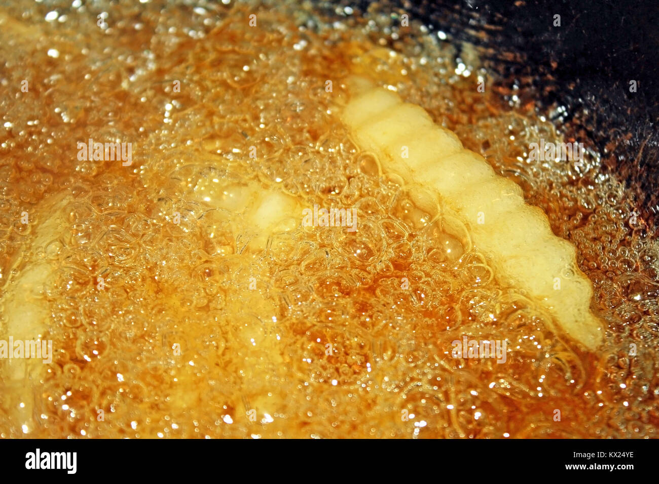 French fries cooking and bubbling in a deep fryer filled with oil Stock