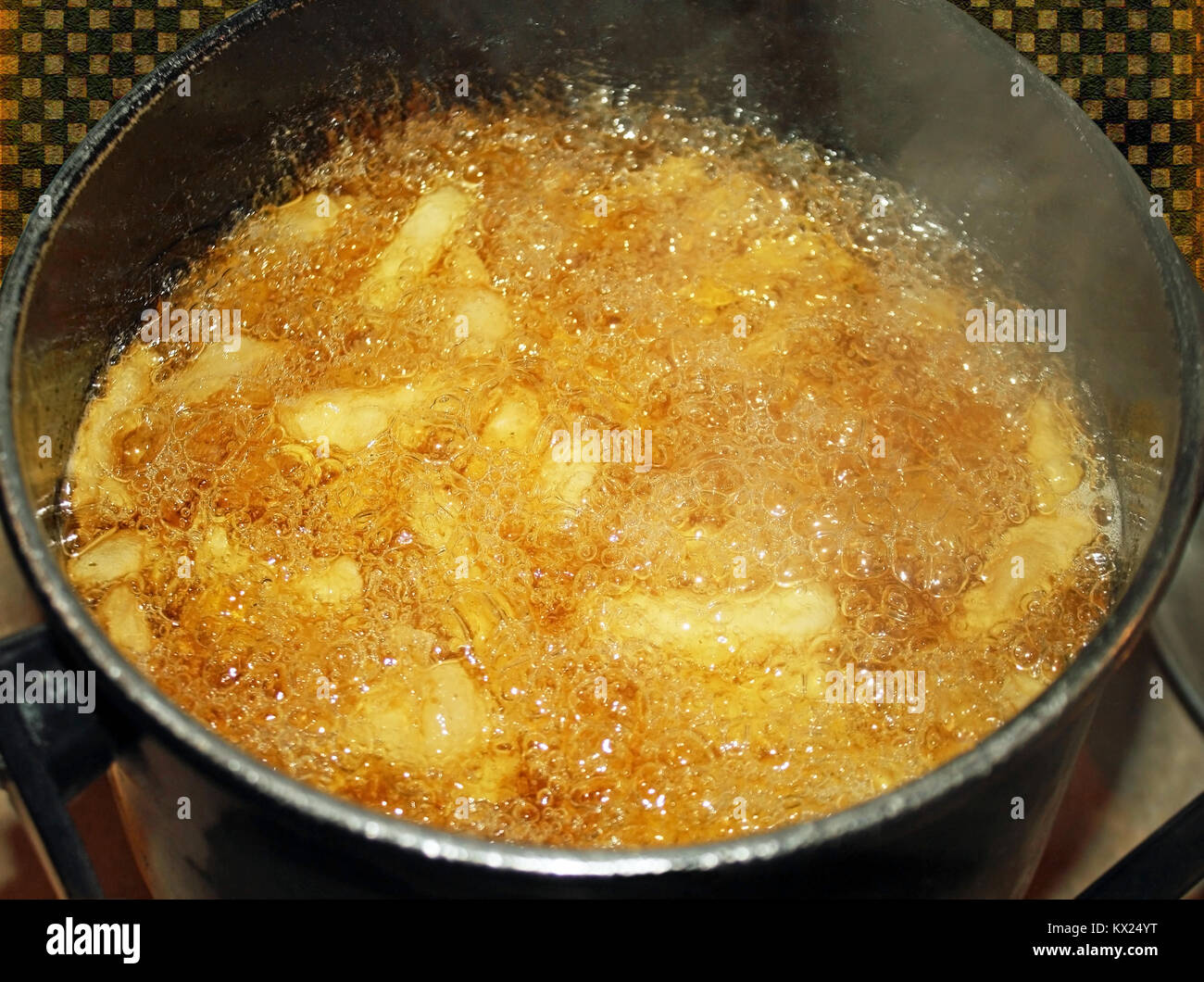French fries cooking and bubbling in a deep fryer filled with oil Stock