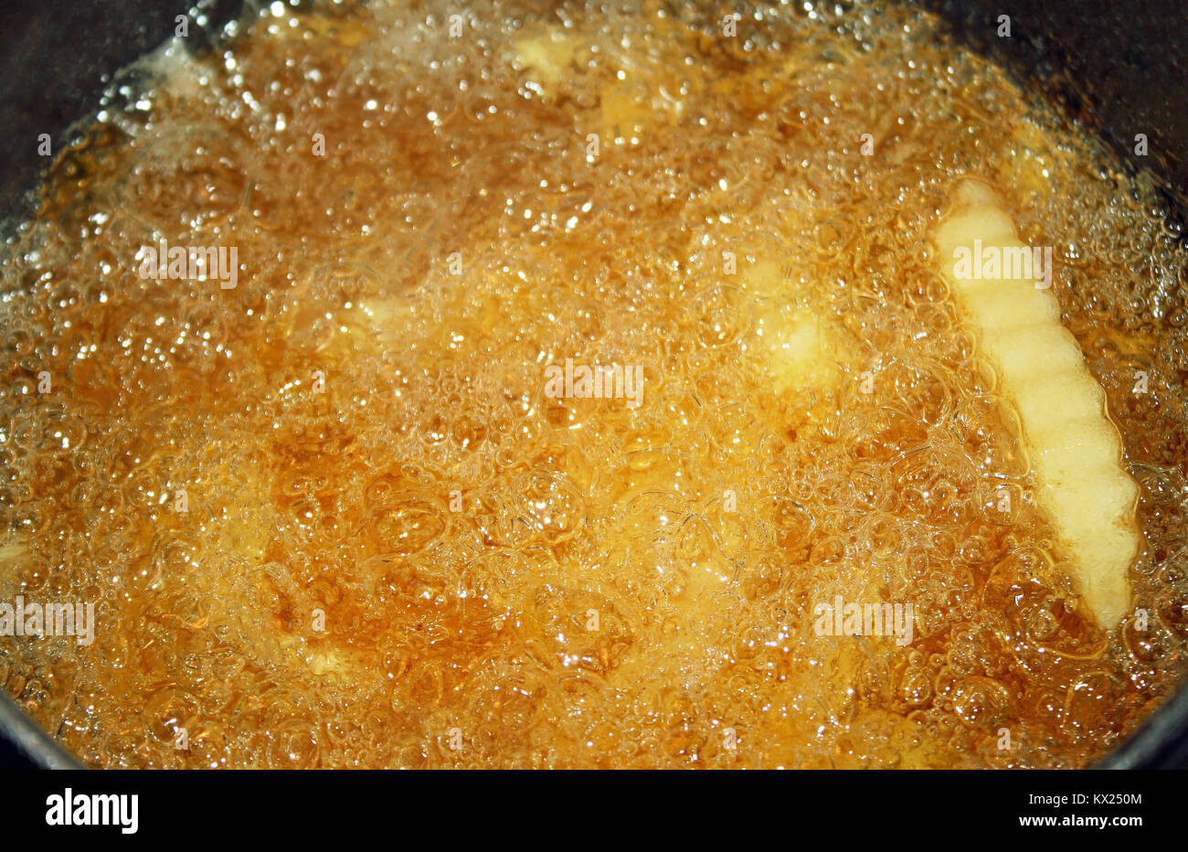 French fries cooking and bubbling in a deep fryer filled with oil Stock Photo