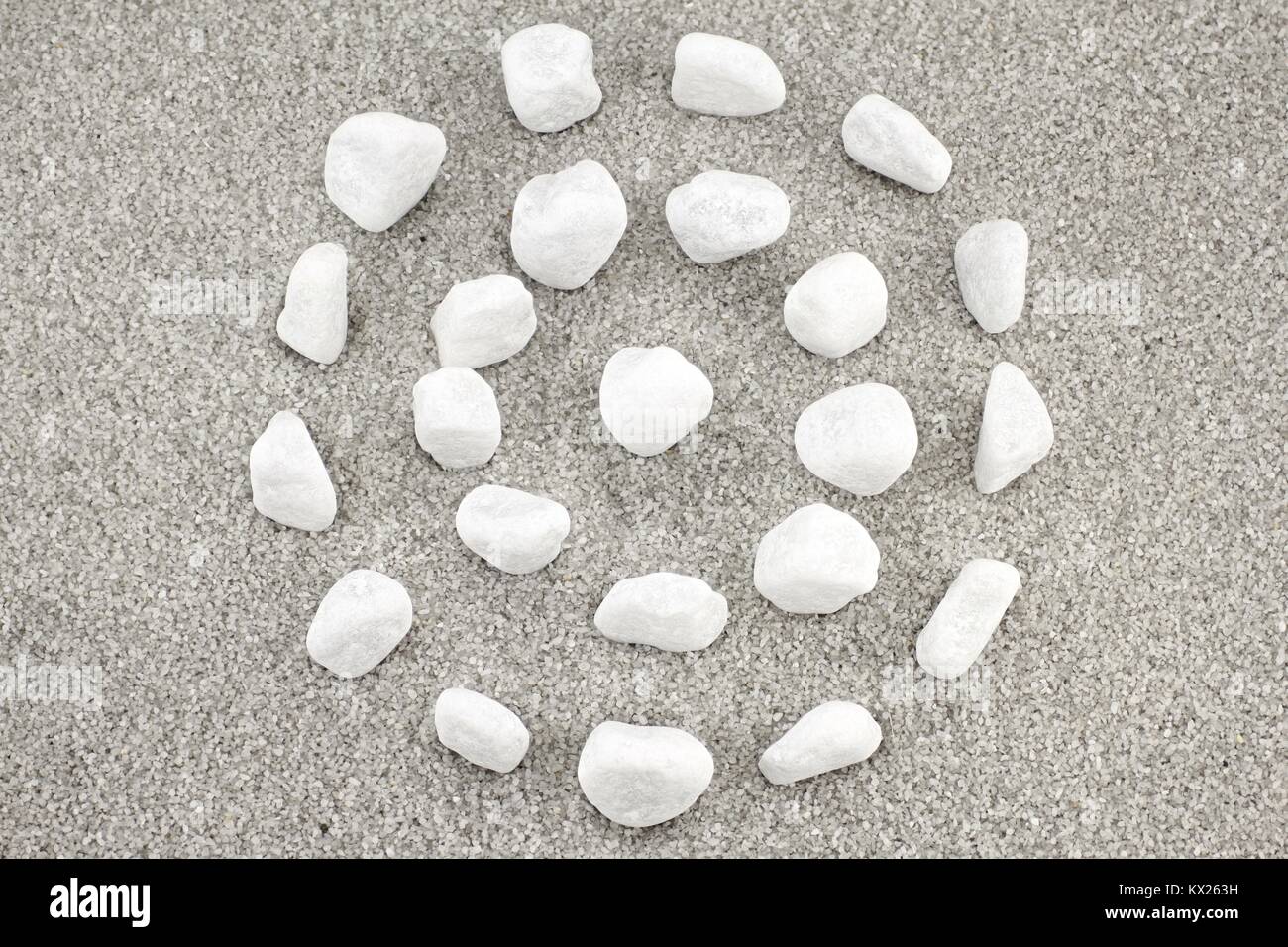 White pebbles in circular shape on gray sand Stock Photo