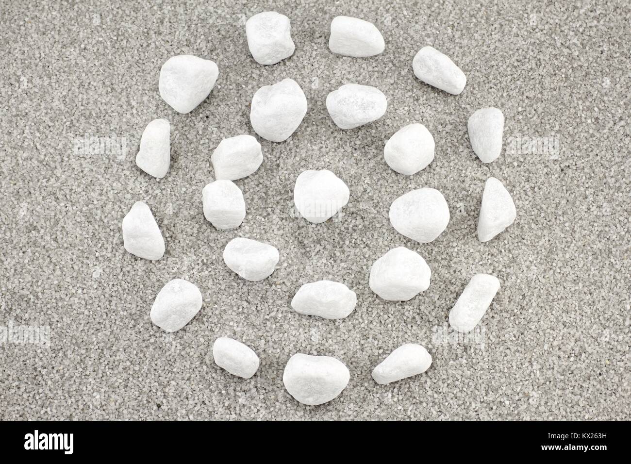 White pebbles in circular shape on gray sand Stock Photo - Alamy