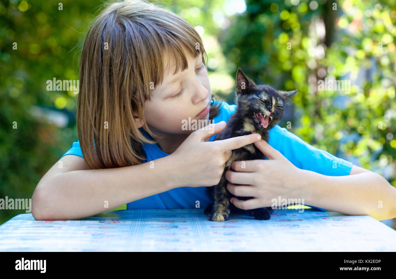 Boy Playing with a Black Kitten at the Table. Stock Photo