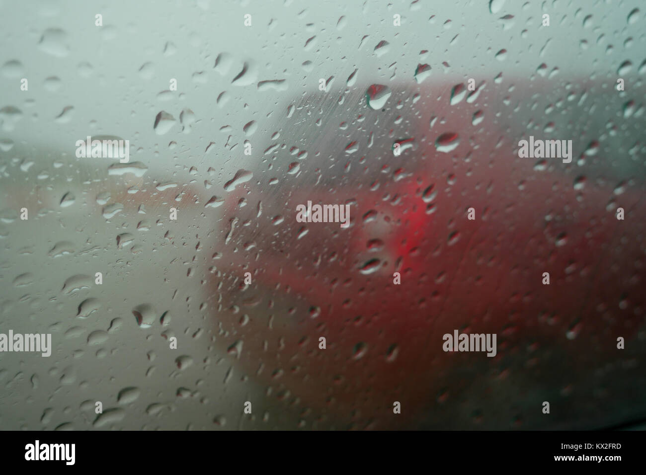 Red car seen through a rain drops covered car glass, Normandy, France Stock Photo