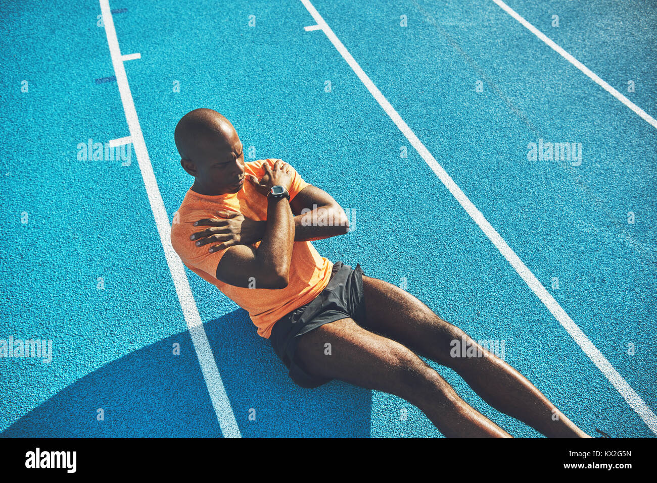 Fit young African male athlete in sportswear sitting on the lanes of a