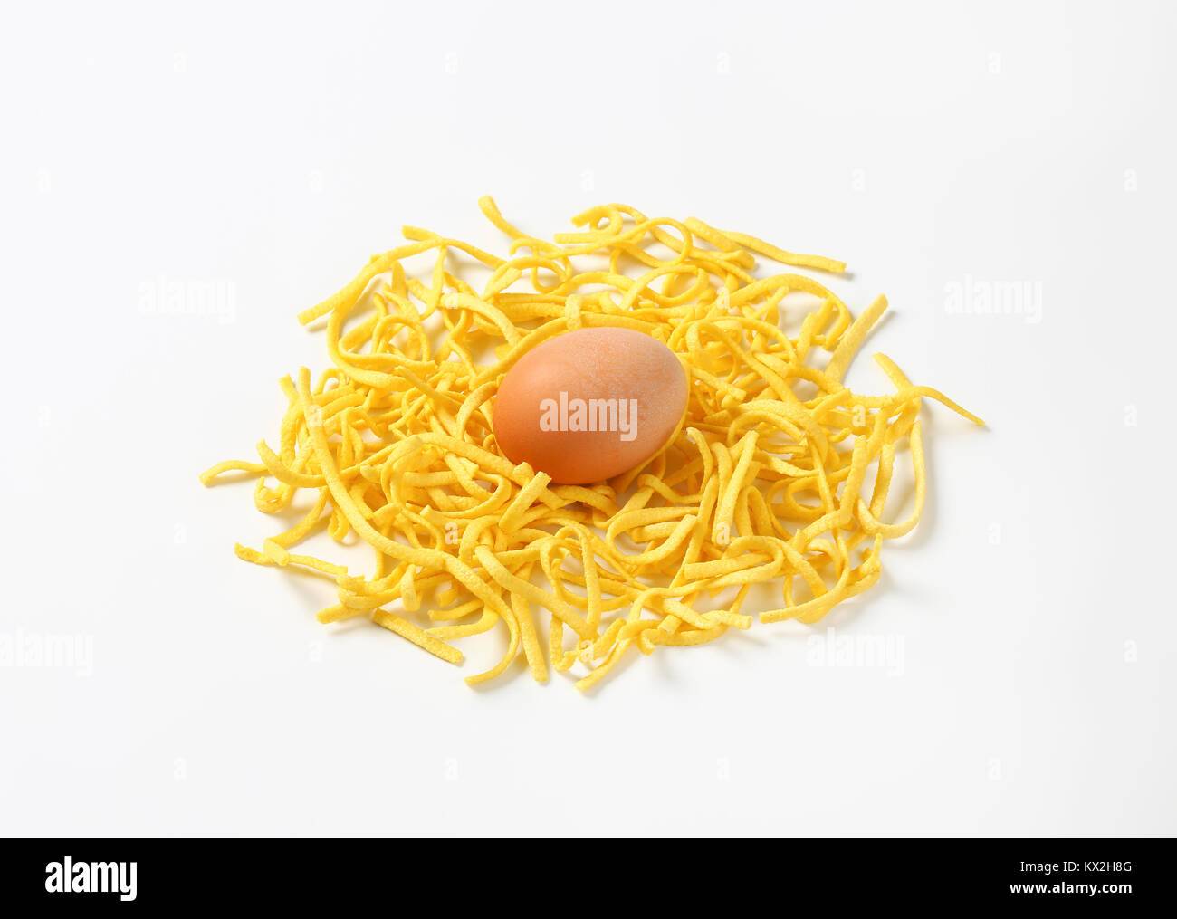 Heap of Dried Egg Noodles (Spaetzle) and Egg on white background Stock