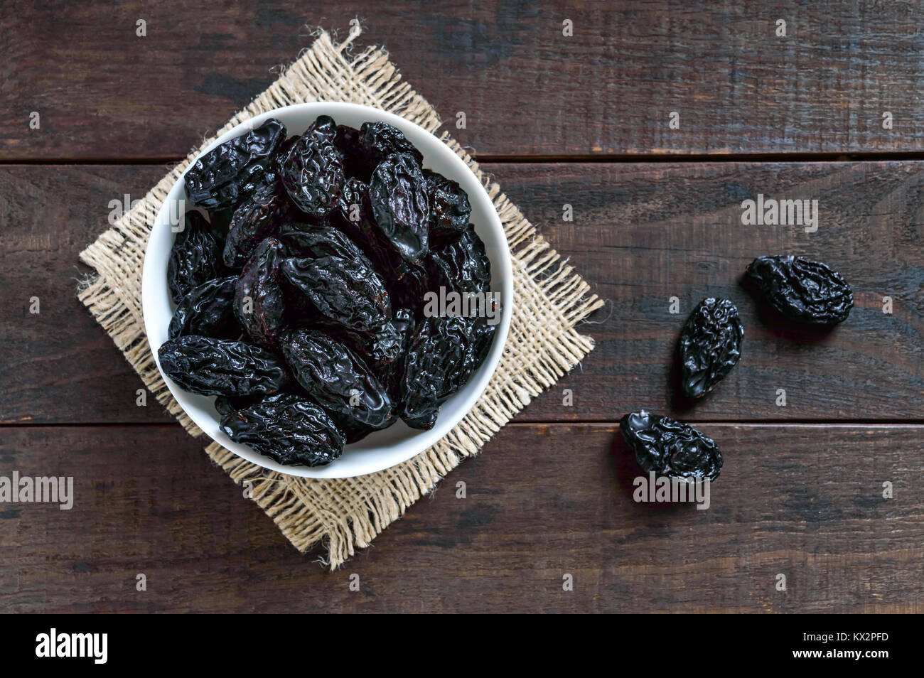 Prunes in a ceramic bowl on a dark wooden background. Dried fruits. The top view Stock Photo