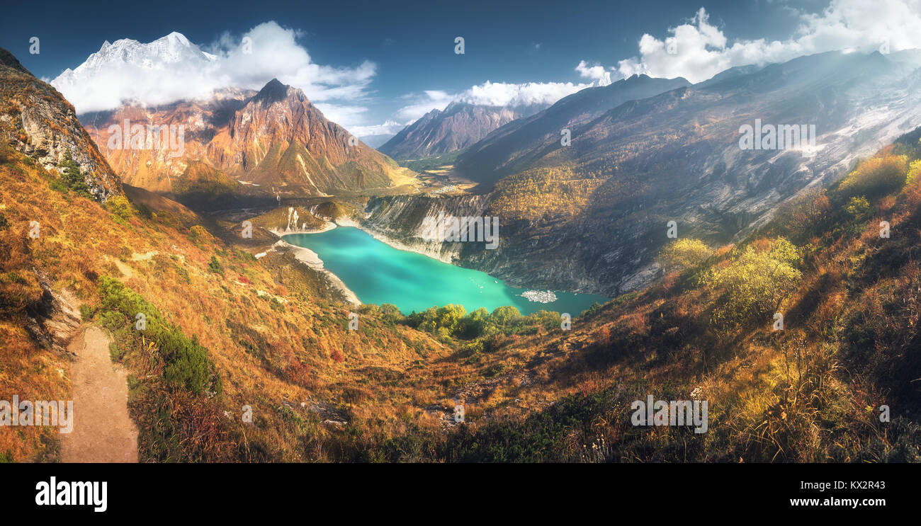Scenic view on high Himalayan mountains, amazing mountain lake with turquoise water, hills, yellow grass, trees and blue sky with clouds at sunset in  Stock Photo