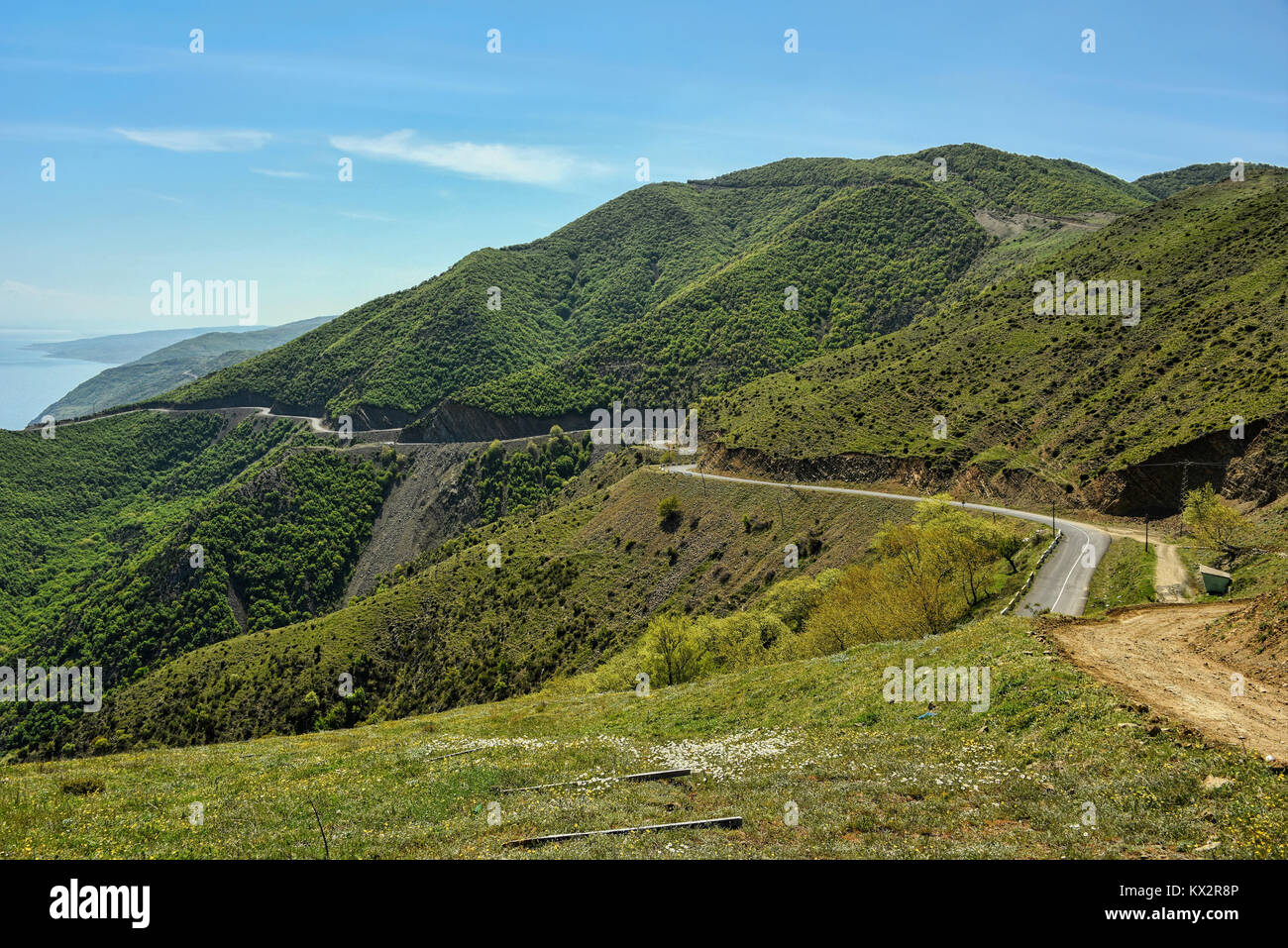 Road winding in green landscape under blue sky with white fluffy clouds ...