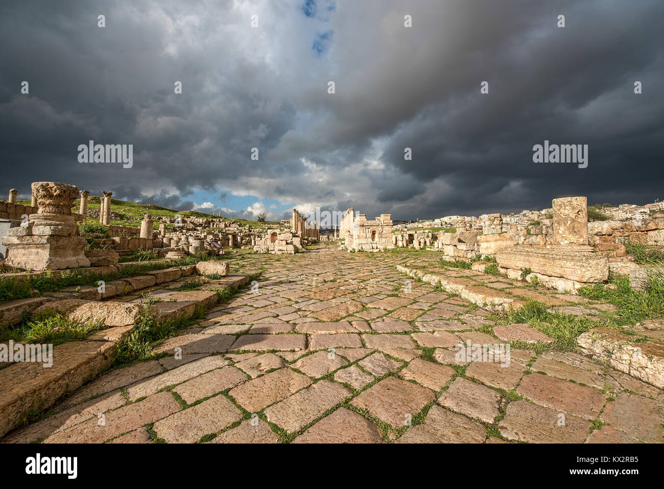 A Roman road in the ancient city of Gerasa after a storm with dark grey clouds Stock Photo