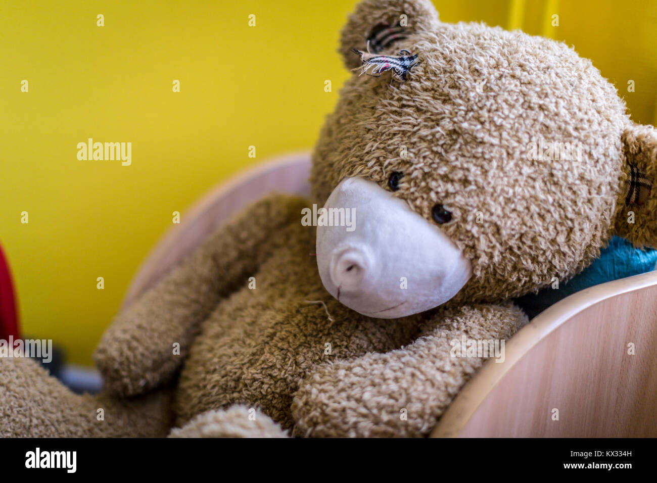 Old teddy bear left alone in a children's chair Stock Photo