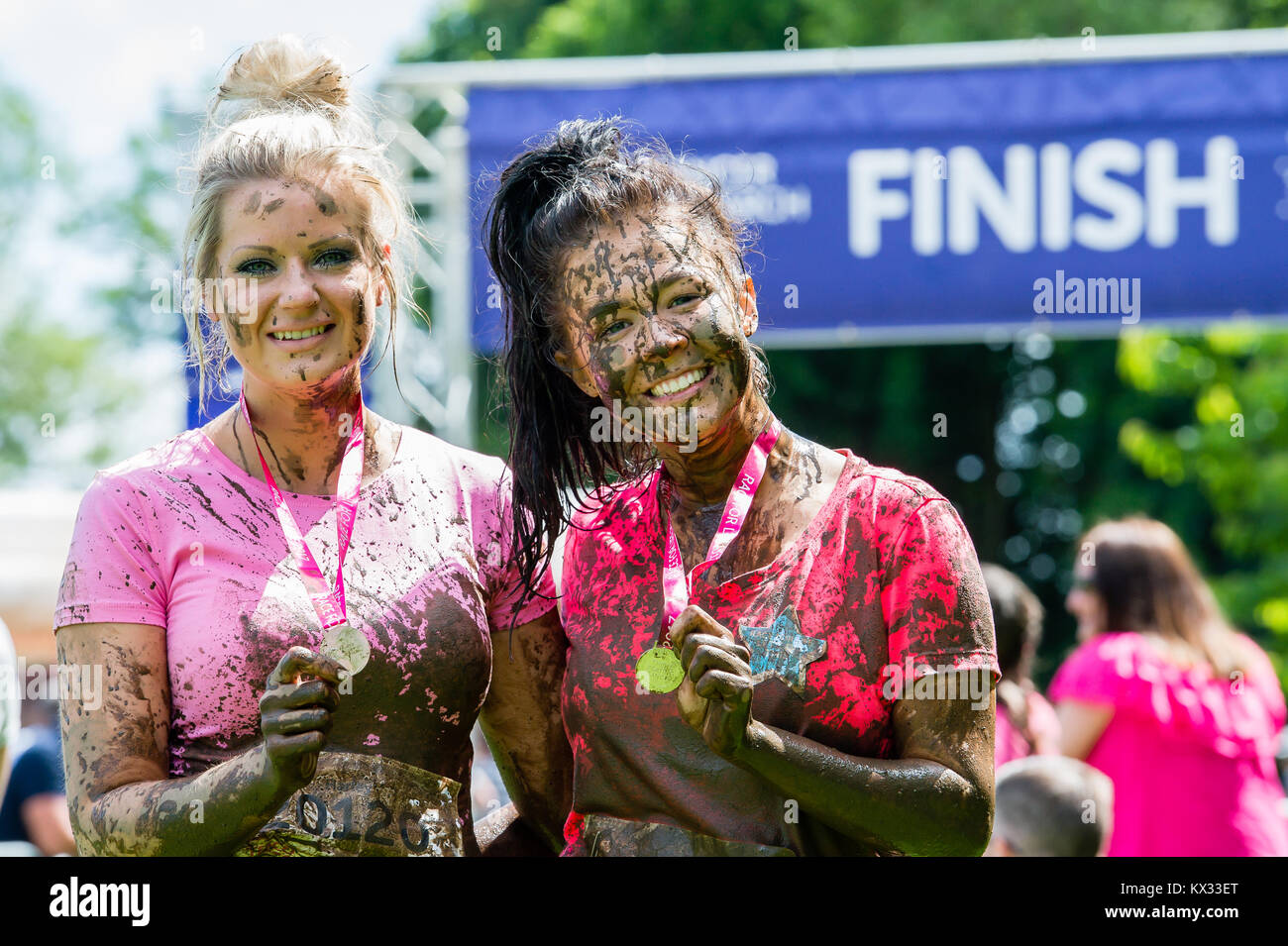 2 friends smiling with their medals after the Pretty Muddy 5k Race for Life charity fun run at Windsor Racecourse 2017 Stock Photo