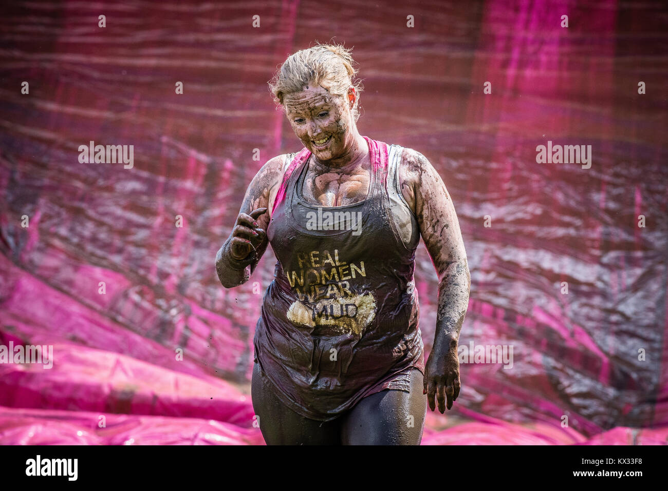 Girls stands up laughing covered in mud during the Pretty Muddy 5k Race for Life charity fun run at Windsor Racecourse 2017 Stock Photo