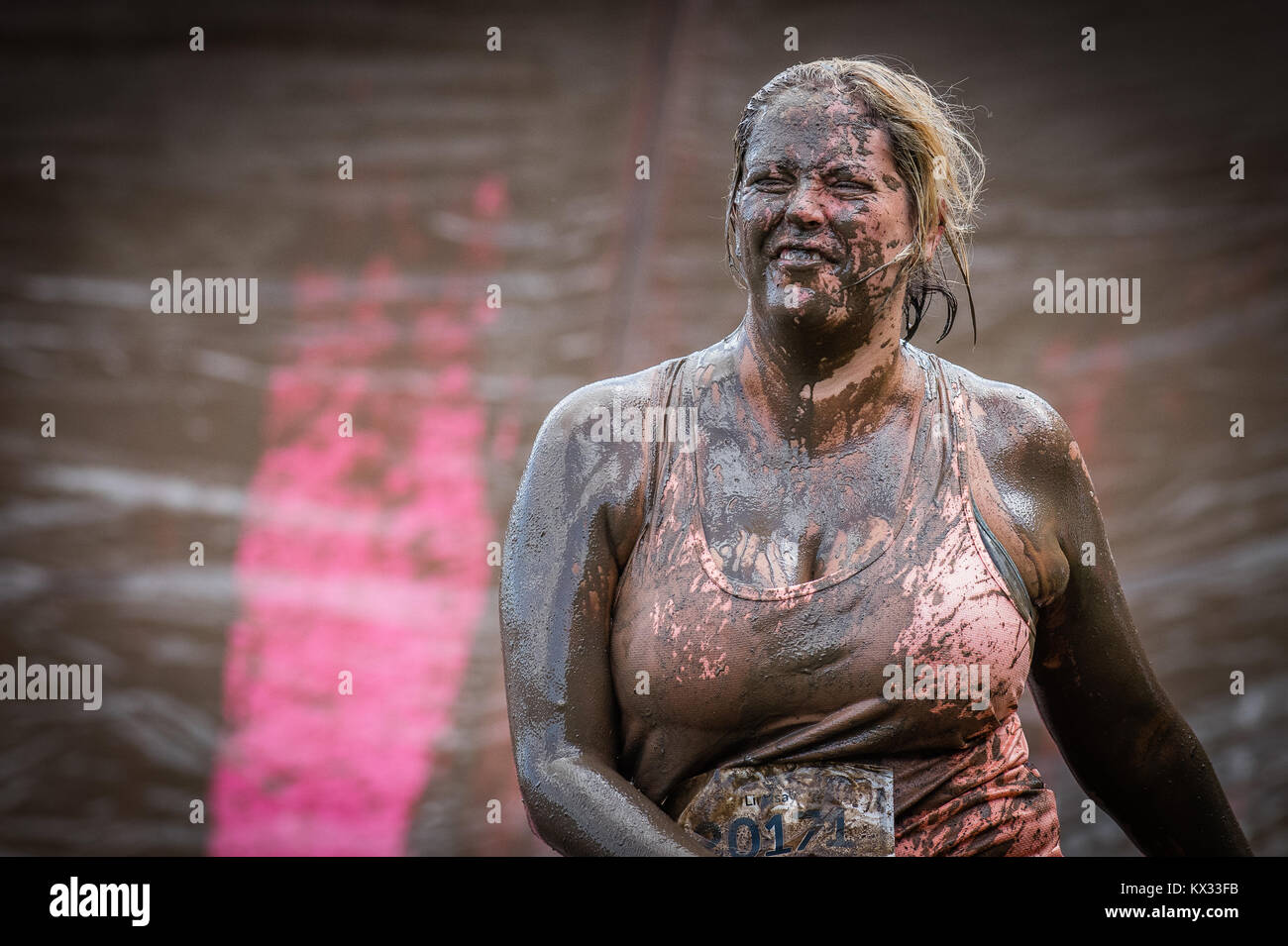 A lady, face covered in mud, walks to next obstacle on the Pretty Muddy 5k Race for Life charity fun run at Windsor Racecourse 2017 Stock Photo