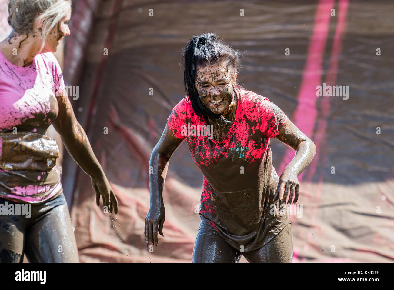 Girls stands up laughing covered in mud during the Pretty Muddy 5k Race for Life charity fun run at Windsor Racecourse 2017 Stock Photo