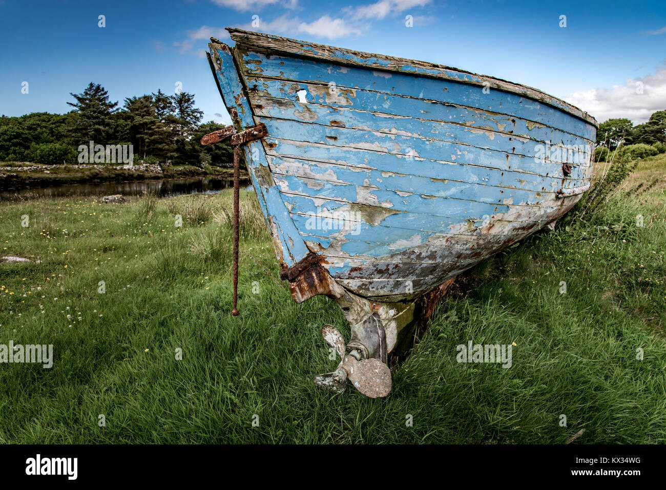 The wreck of a wooden boat is laid on the grass somewhere in Connemara, Ireland. Stock Photo
