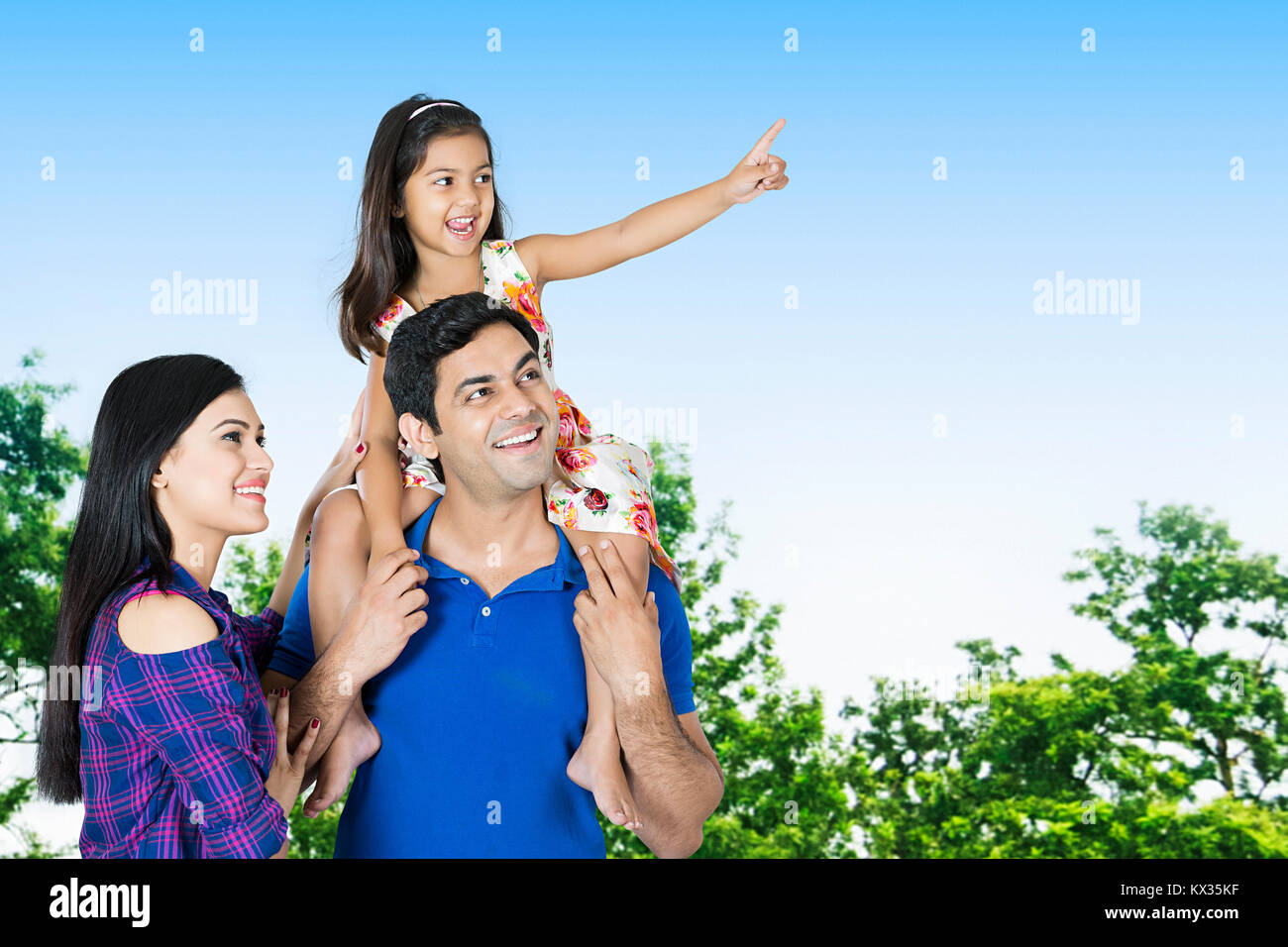 Father carrying Daughter on Shoulders With Mother Pointing Showing Garden Stock Photo