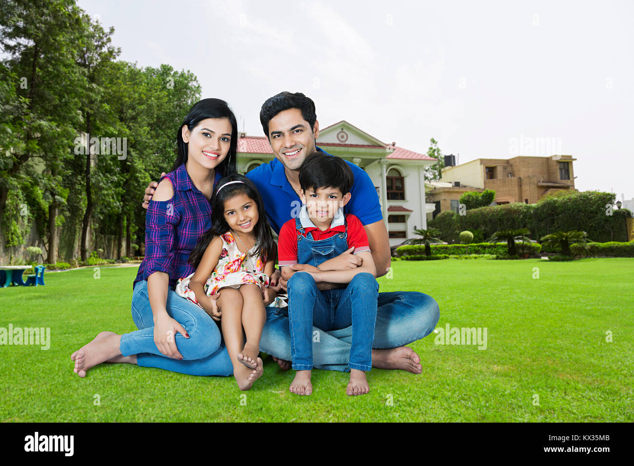 Happy Family Parents And Children Sitting Grass Together Outside Home Stock Photo