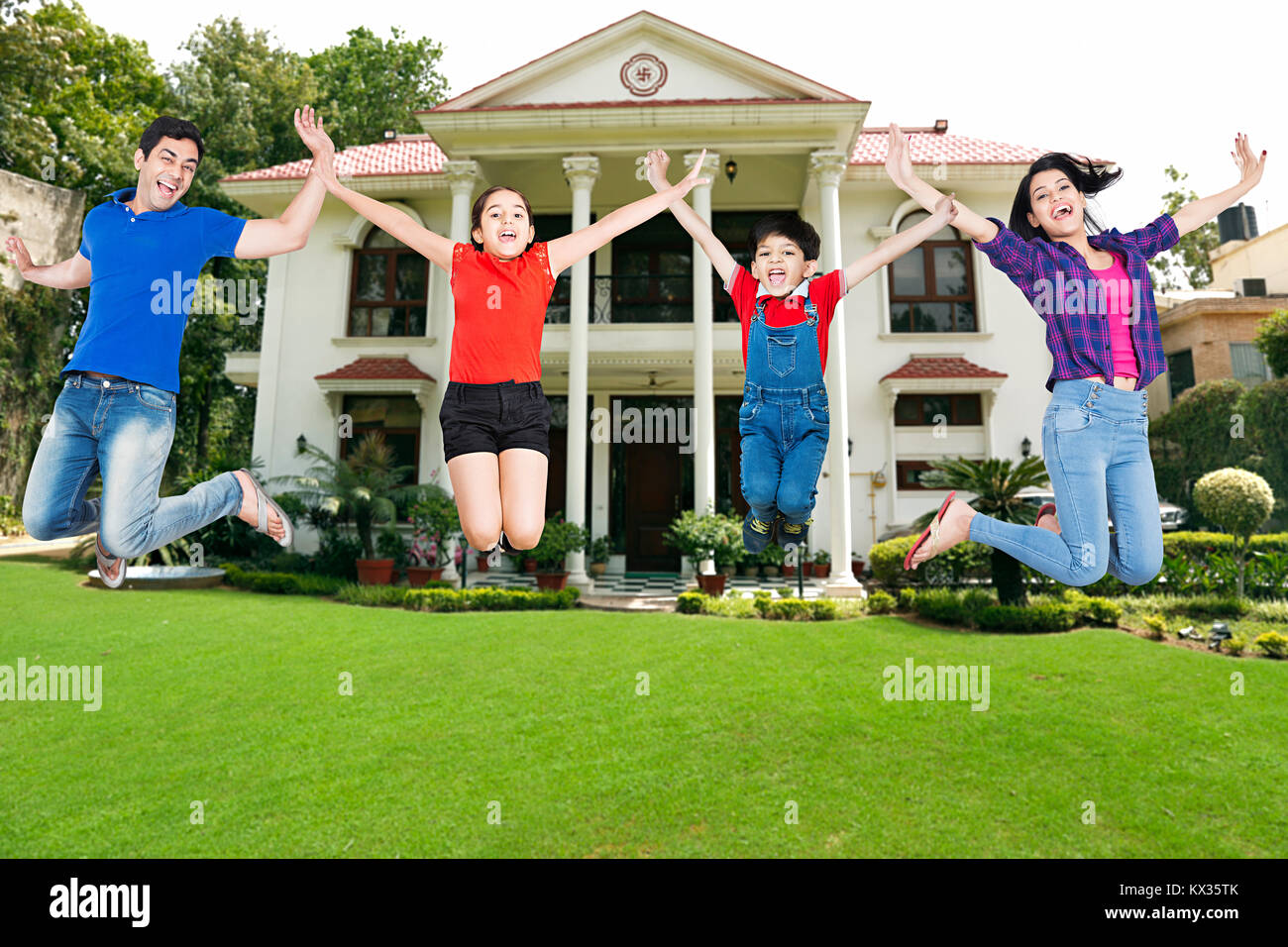 Happy Family, Parents And Kids Jumping Fun Cheerful Courtyard At-Home Stock Photo