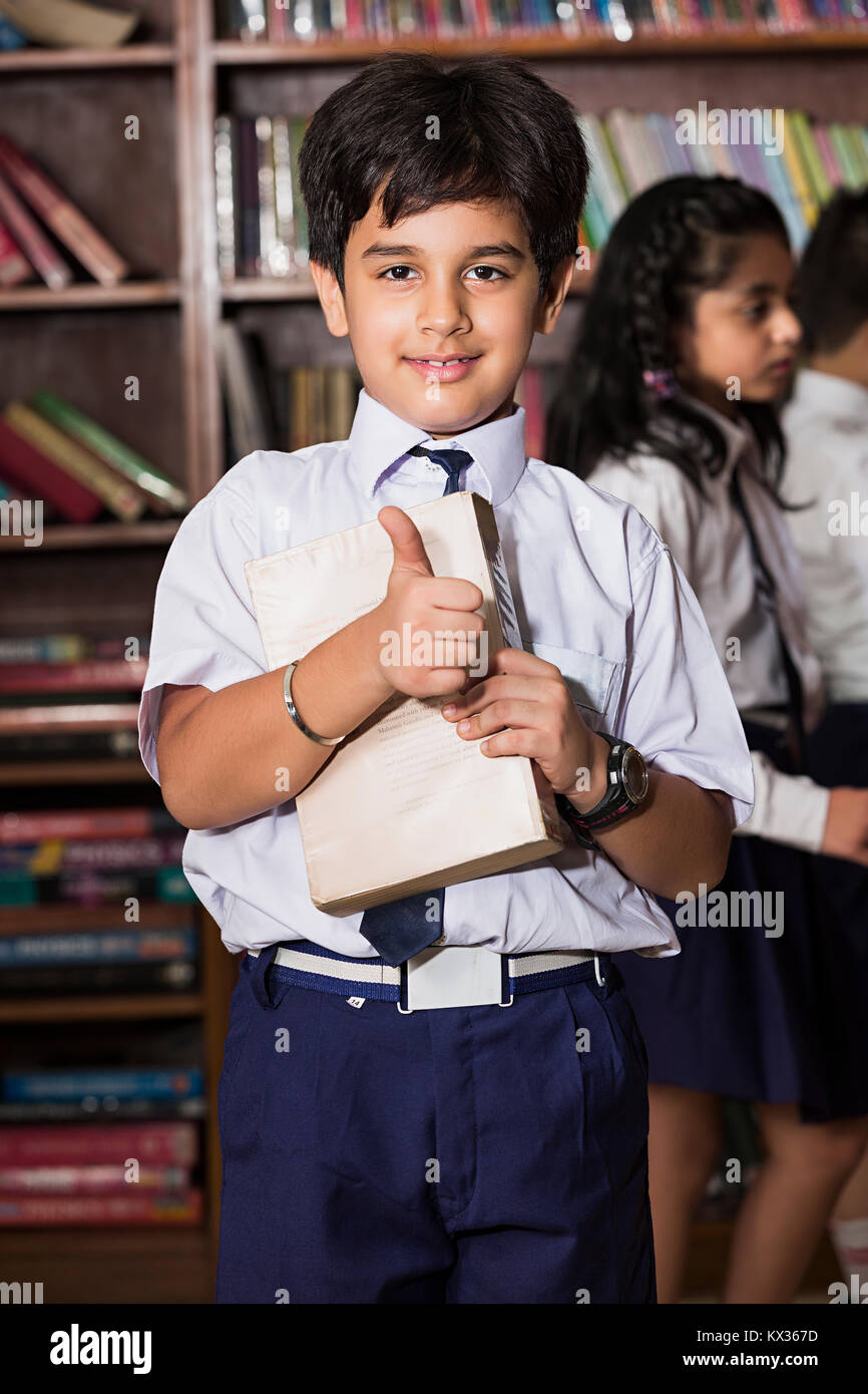 Happy 1 Indian School Little Boy Showing Thumbs up With Book In Library Stock Photo