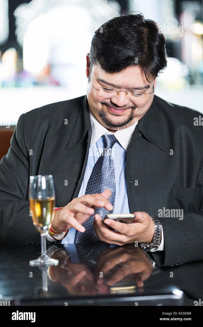 1 Businessman Sitting On Table Reading Text-Message Smartphone In-Hotel Stock Photo