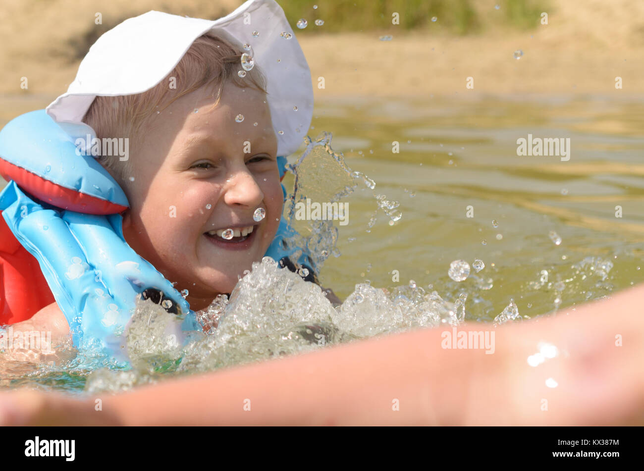A fiveyearold boy in a life jacket is bathing in the lake Stock Photo