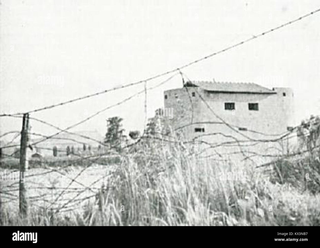 A photograph of a barbed wire fence with a bunker behind it near the Bezigrad area, reflecting the military and defensive installations used in the region, possibly during the Cold War or earlier conflicts. Stock Photo