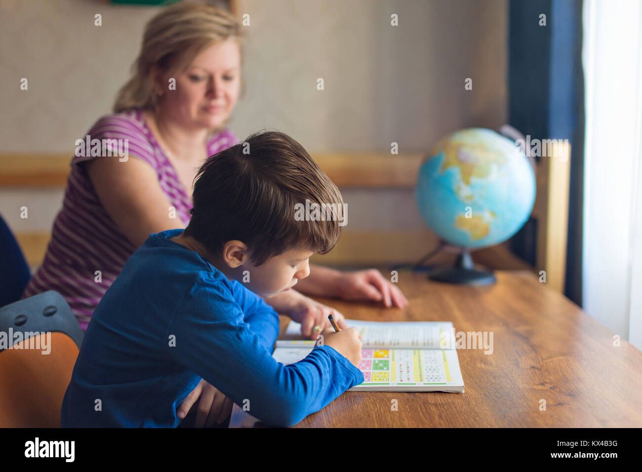 Mother helps son solving mathematics homework at home, parenthood Stock Photo