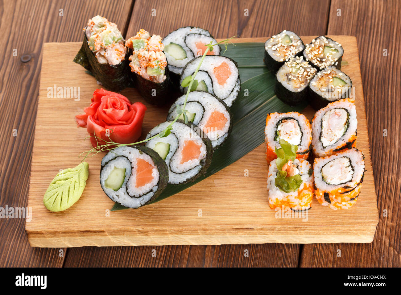 A wooden plate holding different types of sushi pieces. serving sushi