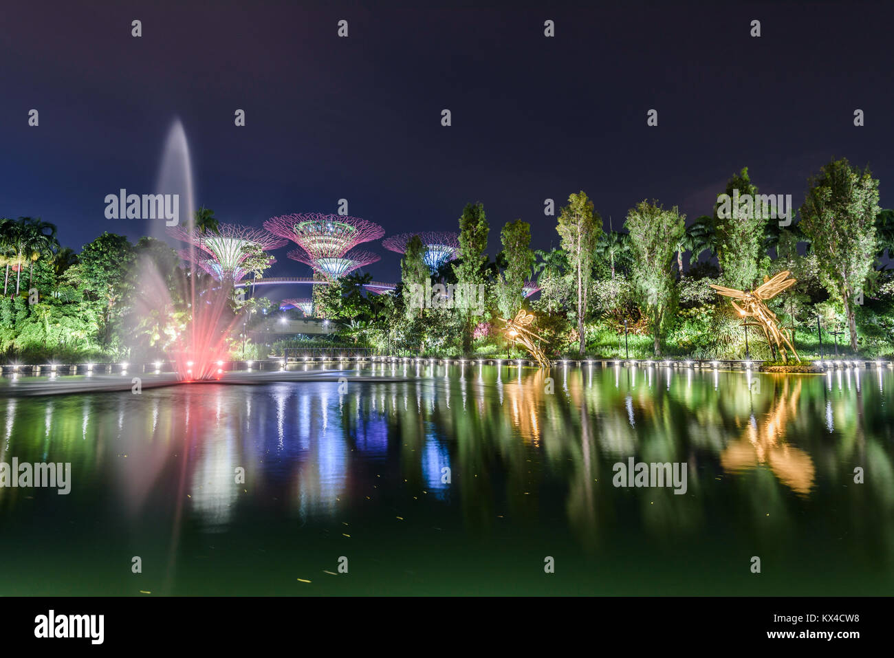 Gardens by the bay lit up at night. In the background the OCBC Skyway and Supertree Grove. In the foreground the Dragonfly Lake. Singapore, March 2017 Stock Photo